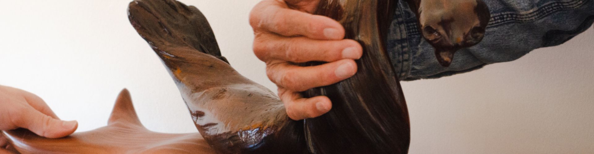 A person exploring a wood sculpture with their hand